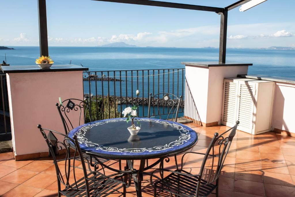 a table and chairs on a balcony with a view of the ocean at Coral Blue Apartment in Piano di Sorrento