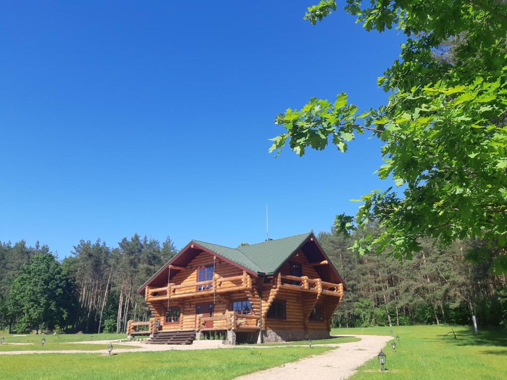 a log cabin in the woods with a blue sky at Poilsio ir sveikatinimo sodyba Pušų Šlamesy in Vilnius