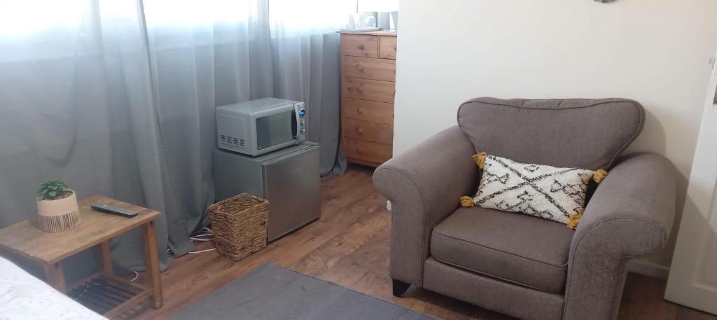 a living room with a chair and a tv at Comfortable double room in London