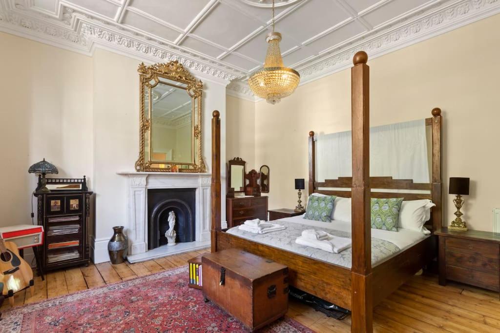 1 dormitorio con cama con dosel y chimenea en Luxurious Victorian, a few minutes from the beach en Hollington