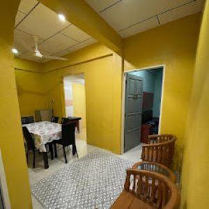 Zimmer mit einem Tisch und Stühlen sowie einer gelben Wand in der Unterkunft Alyaa Homestay in Gua Musang
