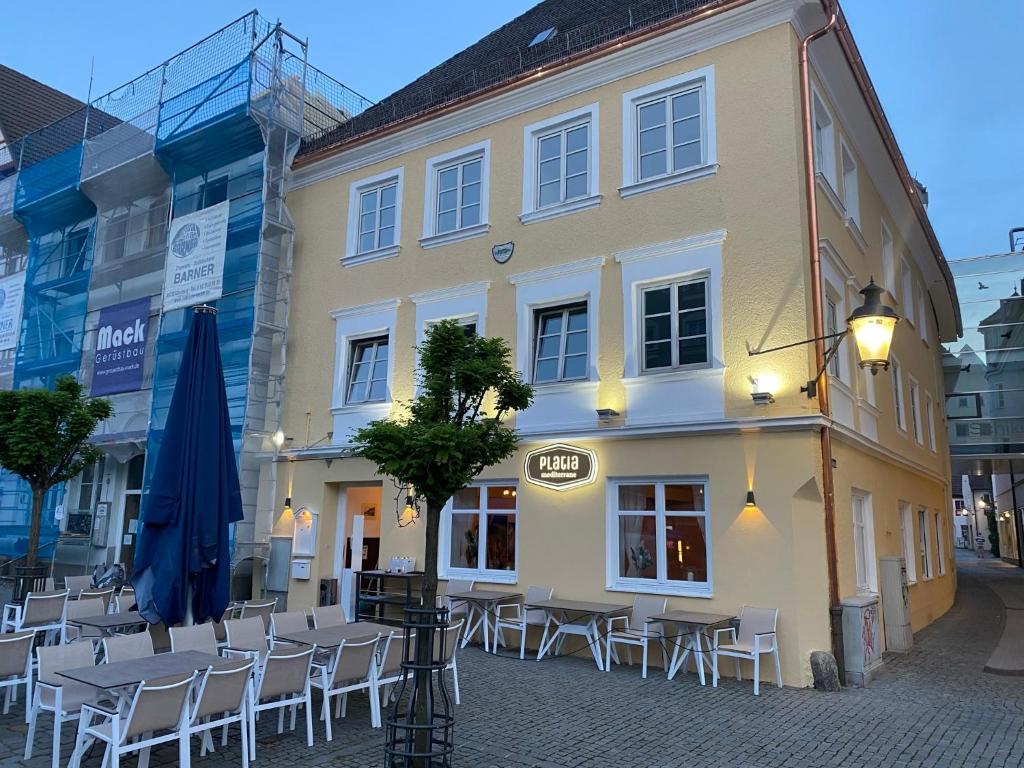 a building with tables and chairs in front of it at Platia - rooms in Günzburg