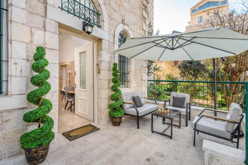 um pátio com um guarda-sol, cadeiras e uma mesa em Nina Luxury Apartment em Jerusalém