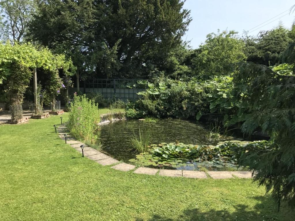 a garden with a pond in the grass at The Old Coach House at Stewton in Louth