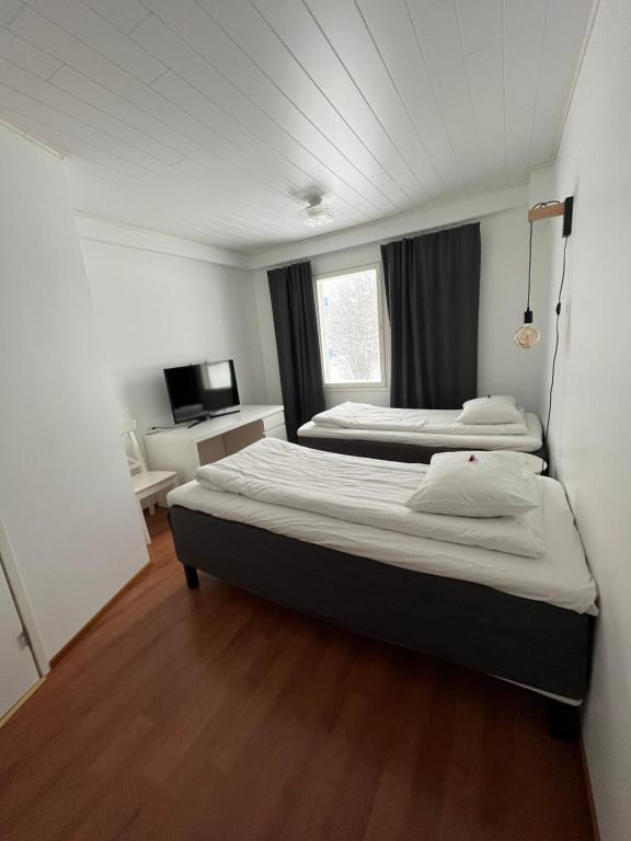 Habitación pequeña con 2 camas y TV. en SEO Motel Alavieska, en Alavieska