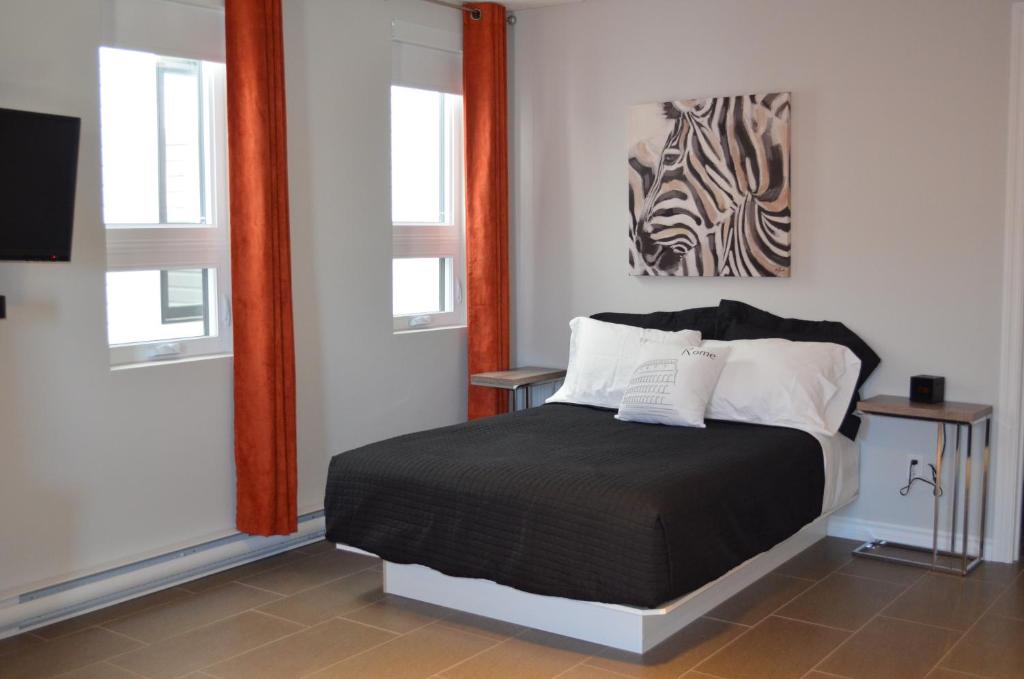 a bedroom with a bed and two windows at Le Chic-Urbain in Rouyn