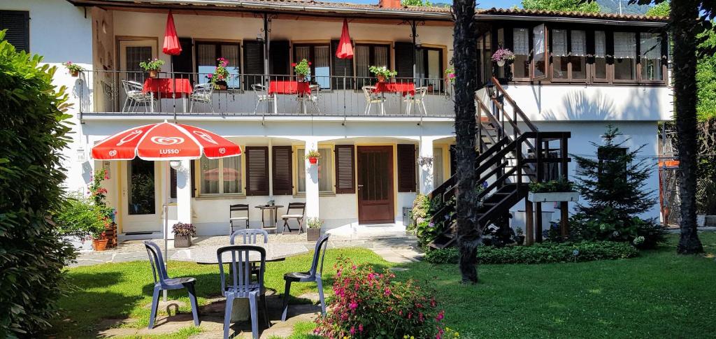 ein Haus mit einer Terrasse mit Stühlen und einem Sonnenschirm in der Unterkunft Garni Molinazzo in Agno