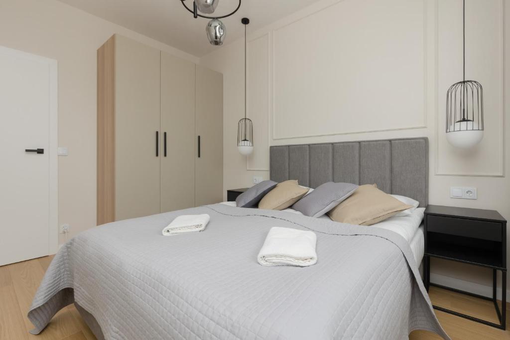 ein weißes Schlafzimmer mit einem großen Bett mit zwei Handtüchern darauf in der Unterkunft Wola Spacious Flat with Air Conditioning & Balcony by Renters in Warschau