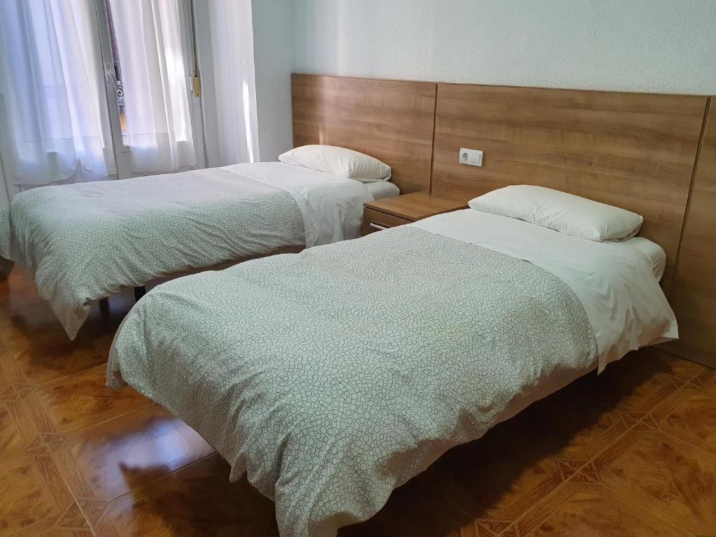 2 camas en una habitación de hotel con sábanas blancas en Hostal Zamorán en Madrid