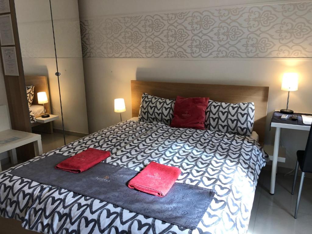 a bedroom with a bed with two red pillows on it at Mandula Apartman in Cegléd