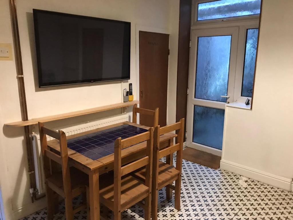 um quarto com uma mesa e duas cadeiras e uma televisão em Coronation Place em Troed-y-rhiw