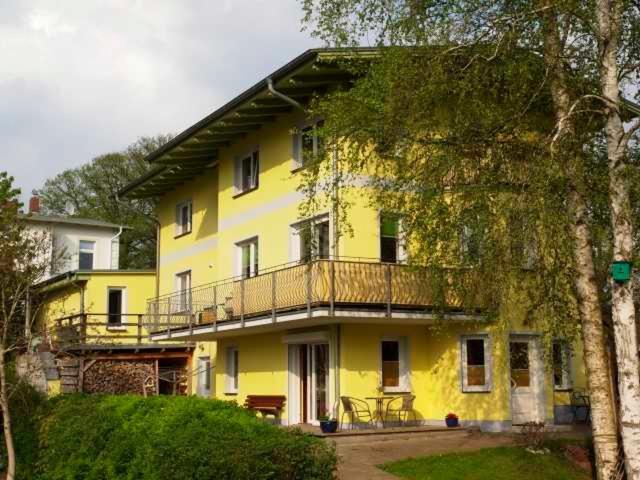 Una casa amarilla con balcón en la parte superior. en Ferienwohnung Bergstraße 04 Whg 02, en Ahlbeck