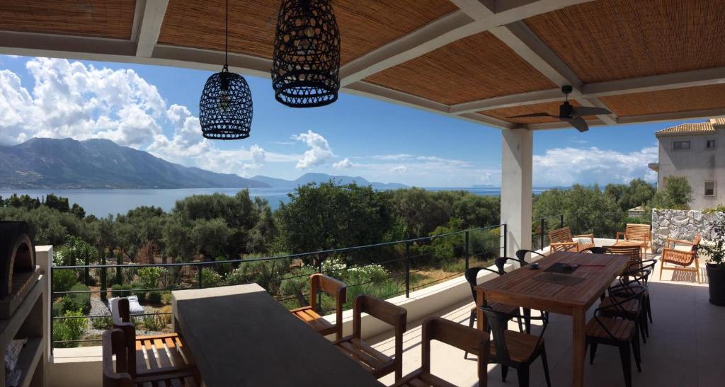 balcón con mesa, sillas y vistas al lago en Villa Mytikas, luxury in Greece with seaview and heated pool & jacuzzi, en Pogoniá