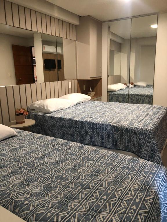 Habitación de hotel con 2 camas y espejo en Flat beira mar Manaíra, en João Pessoa