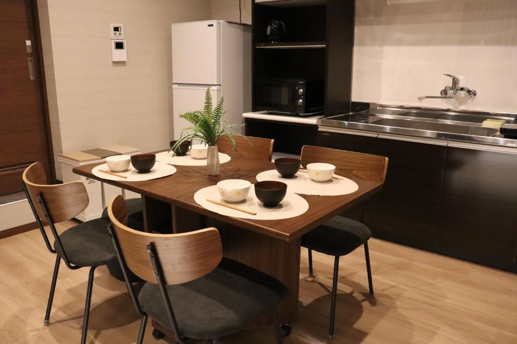 einen Holztisch in einer Küche mit Stühlen und Tassen in der Unterkunft Linore in Ginowan