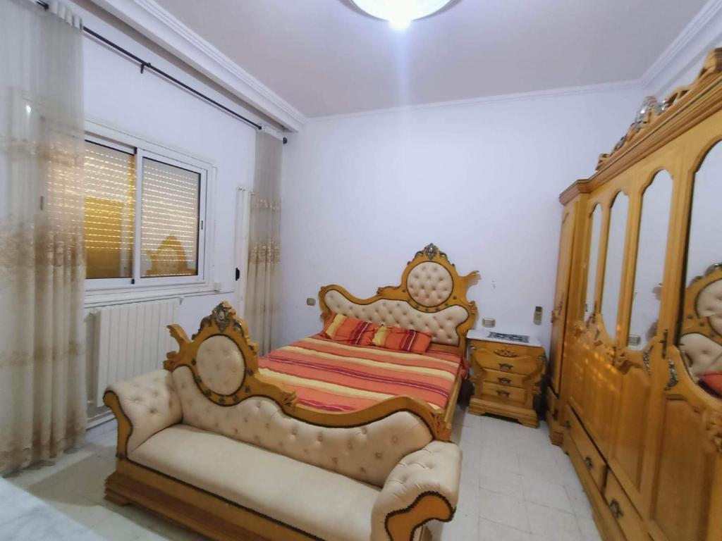 a bedroom with a king sized bed and a dresser at S+2 skanes RDC enozha in Monastir