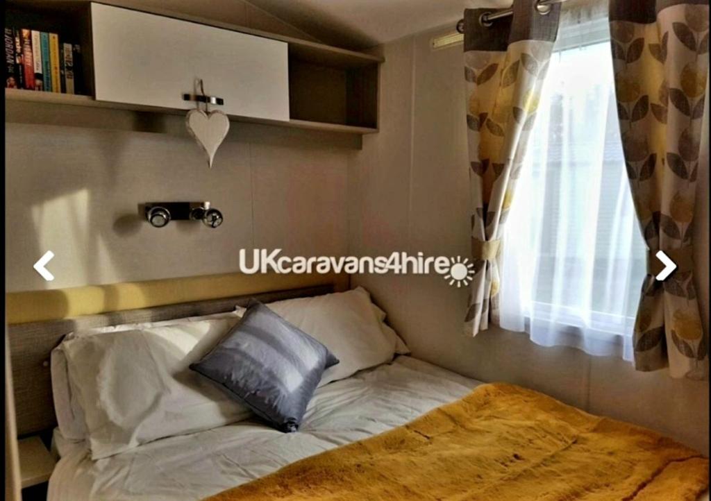 a bed in a small room with a window at Susie's Beautiful Caravan near the sea in Pwllheli