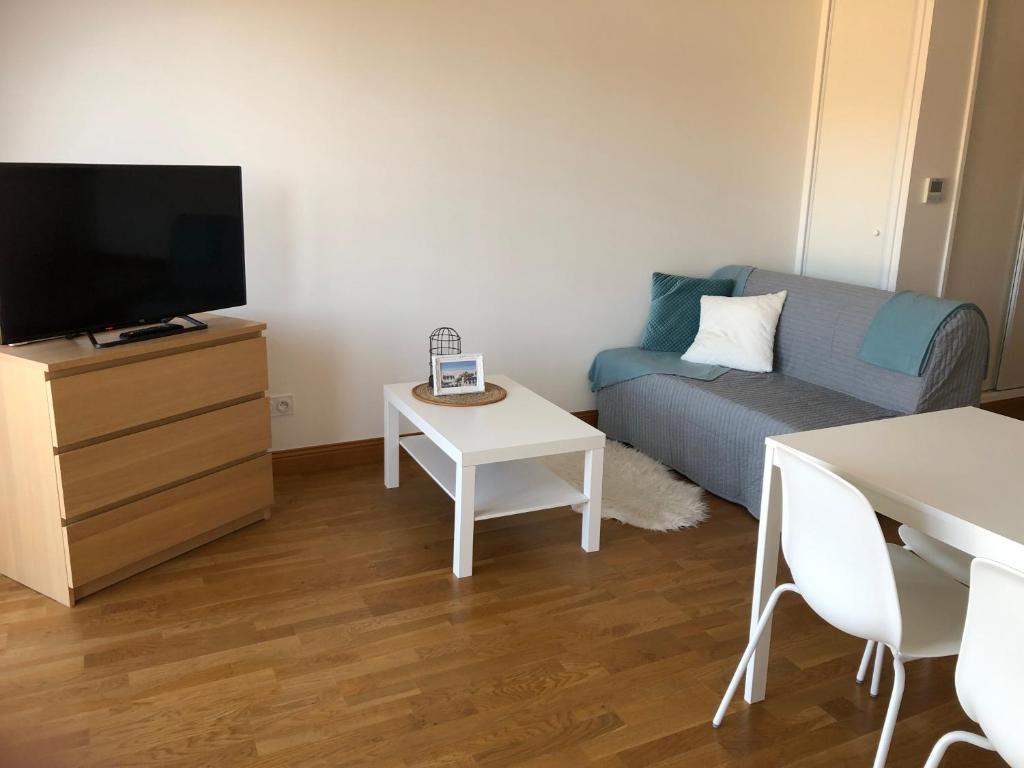 a living room with a couch and a tv and a table at Villa Médicis Trouville-sur-mer in Trouville-sur-Mer