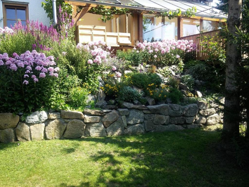 een tuin met bloemen en een stenen muur bij FW Rettenberger in Rinchnach