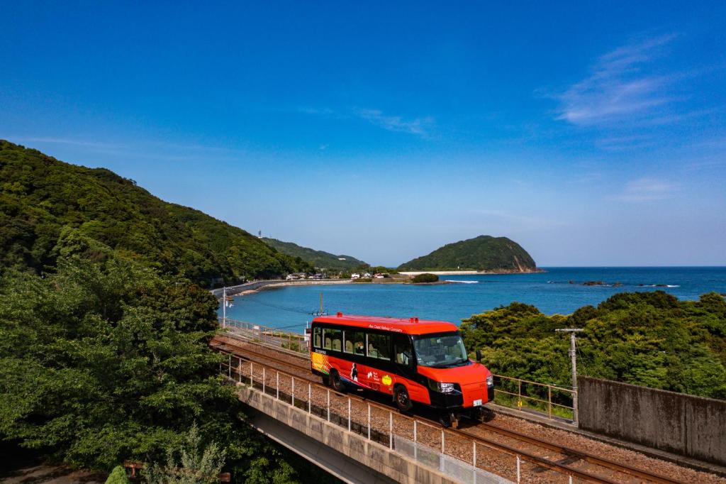 un autobús rojo en un puente cerca del océano en Guest House Fuku-chan, en Kaiyo