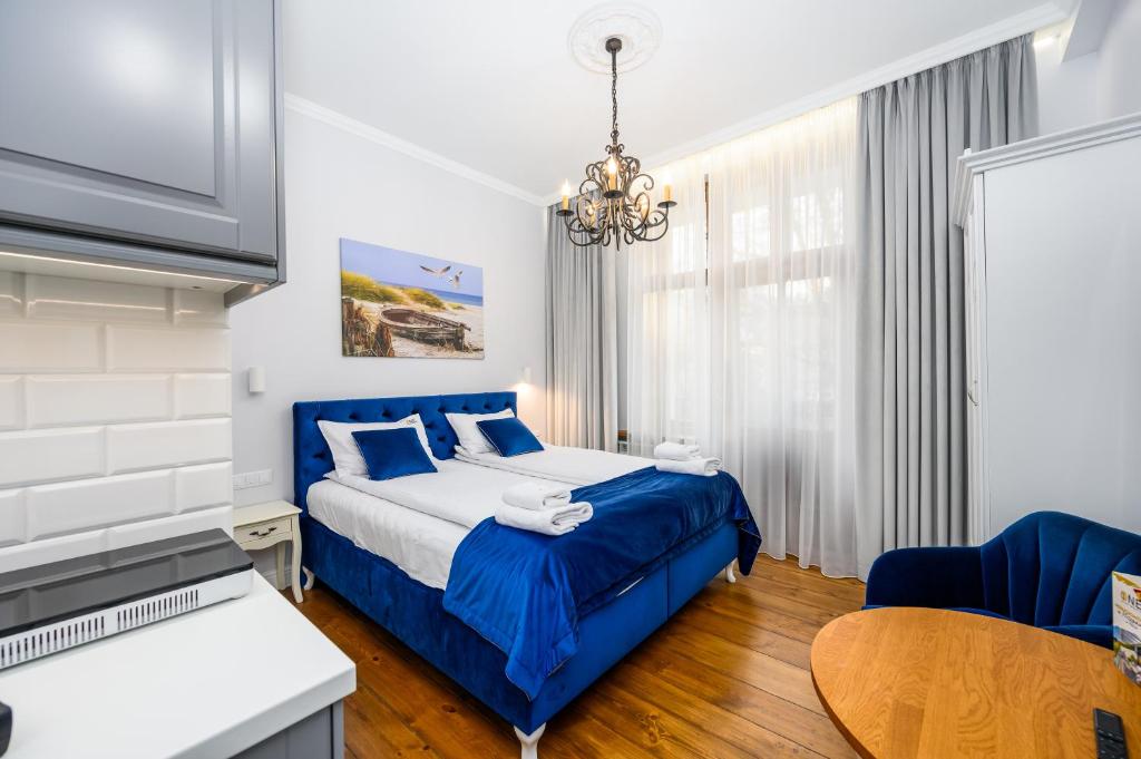 Schlafzimmer mit einem blauen Bett und einem Tisch in der Unterkunft Sea Sopot Apartments by OneApartments in Sopot