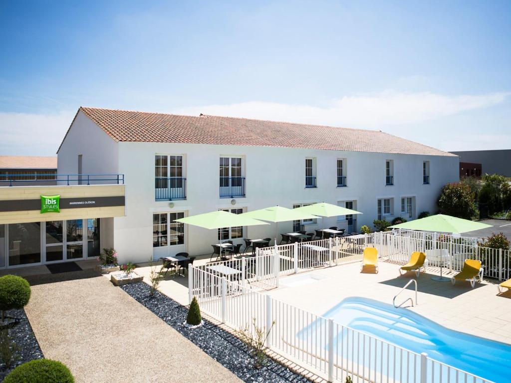 a hotel with a swimming pool in front of a building at ibis Styles Marennes d'Oléron in Marennes