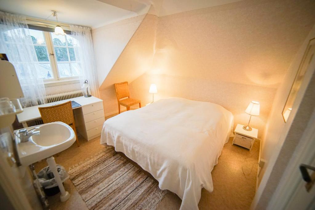 a bedroom with a white bed and a sink at Liljeholmen Herrgård Hostel in Rimforsa