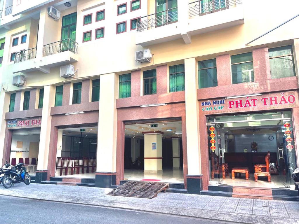 a tall building with windows and a plant shop at Nhà nghỉ Phát Thảo in Ha Tien