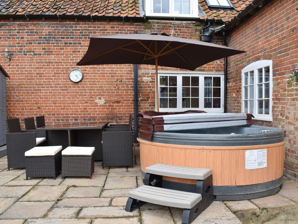 a hot tub with an umbrella and a table and bench at Middle Farm in East Harling