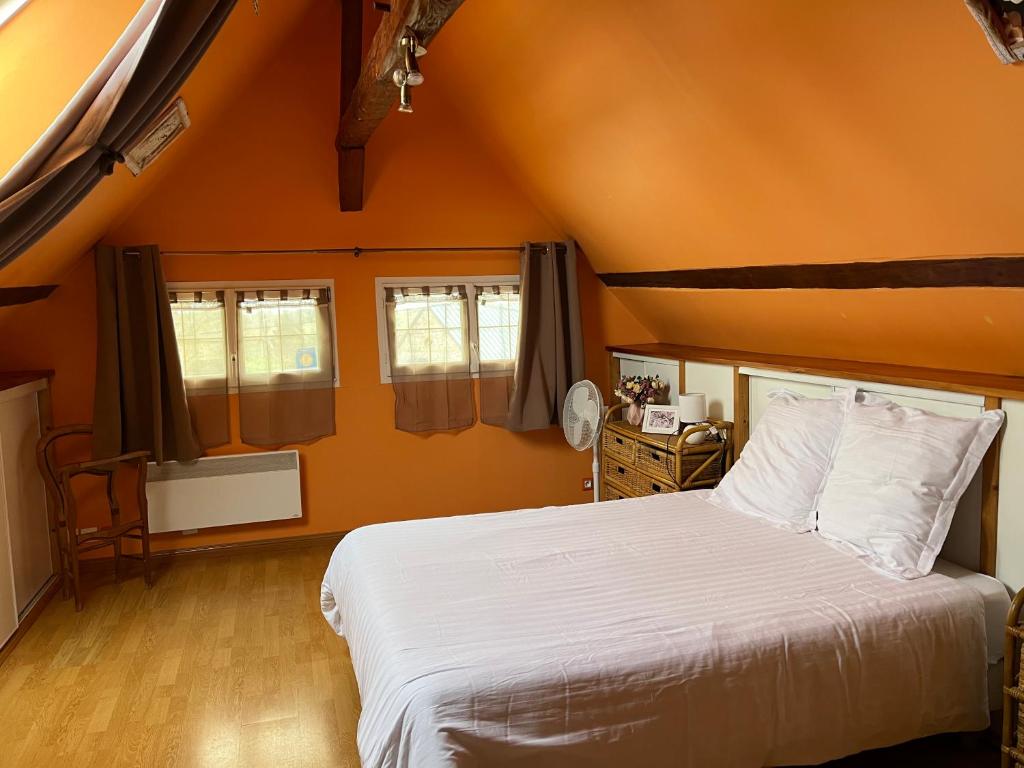 a bedroom with an orange room with a bed and windows at LES FLORALIES in Froberville