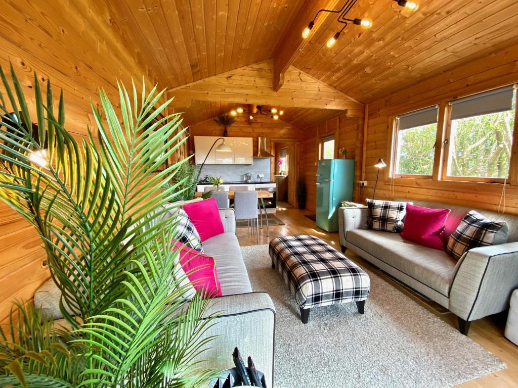una sala de estar con sofás y una cocina en una cabaña en Yealm Cabin Self Catering Log Cabin in Devon with Hot Tub en Plymouth