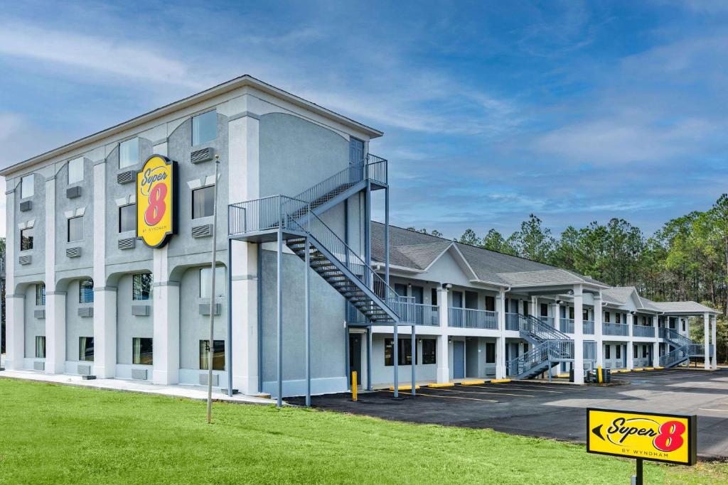 un gran edificio blanco con un cartel delante en Super 8 by Wyndham Moss Point, en Moss Point