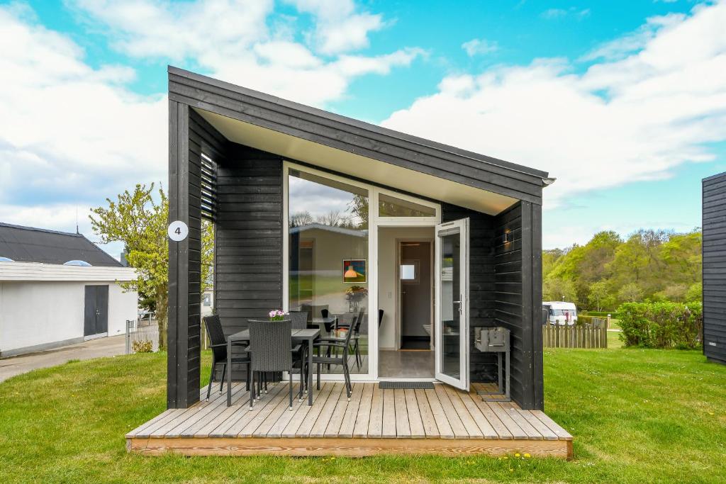 una pequeña casa negra con terraza de madera en First Camp Skovlund Camping & Cottages, en Båring