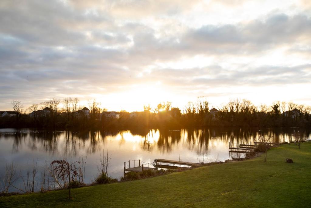 a view of a lake at sunset with a dock at Stunning lodge on the lake in South Cerney