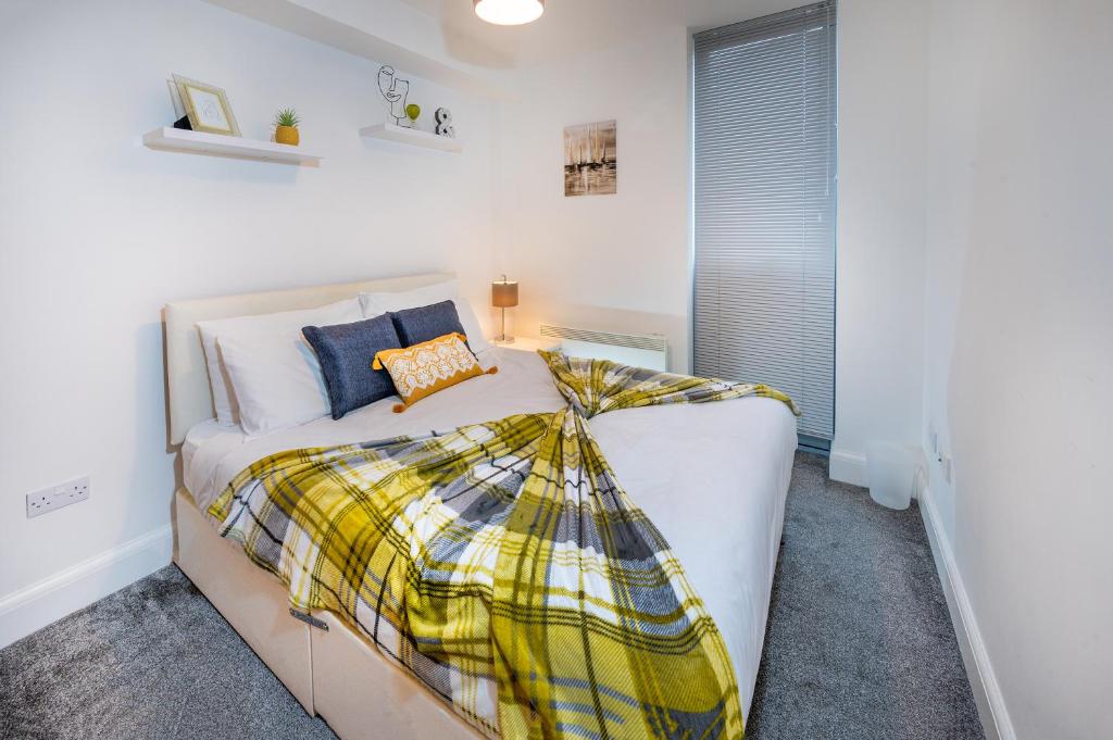 Modern & spacious 2-bed flat with secure parking في ريدينغ: غرفة نوم بسرير ابيض وبطانية منقوشة