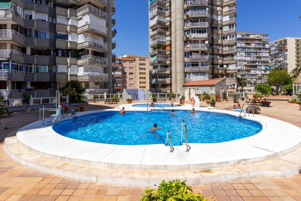 a large pool with people in it in front of apartment buildings at Apt Playa y Montaña in Torremolinos