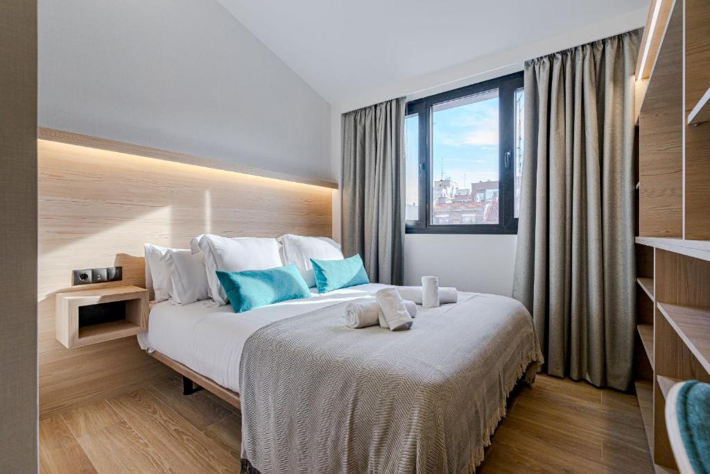 um quarto com uma cama grande e almofadas azuis em Feelathome Ventas Suites em Madri