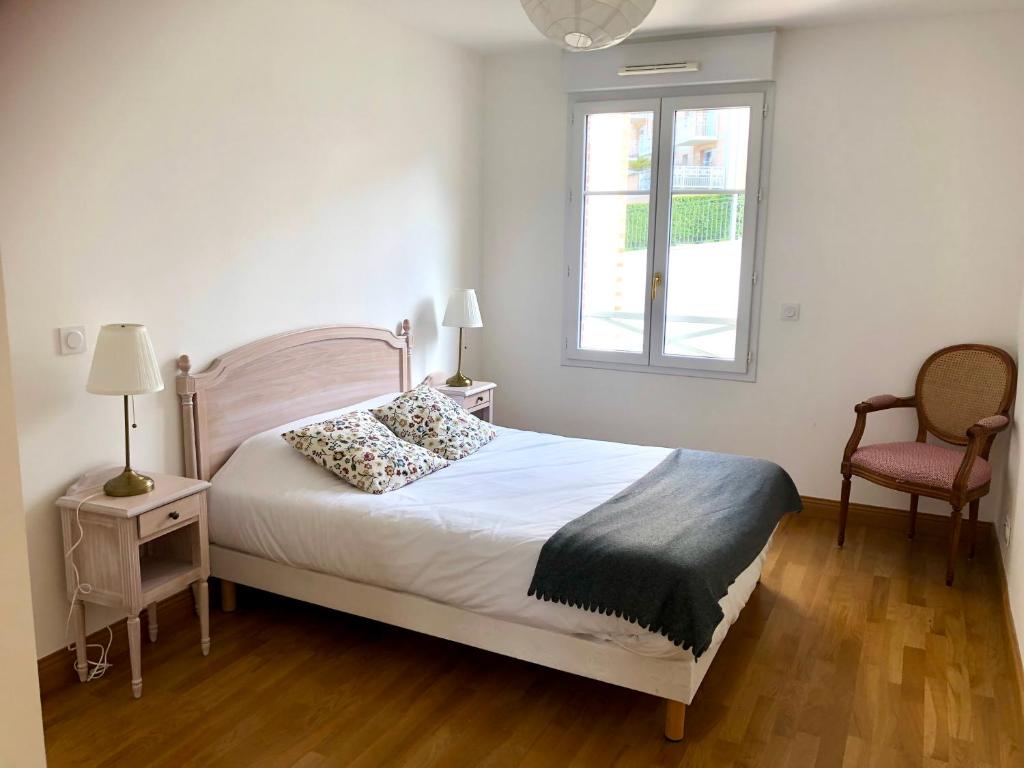 a bedroom with a bed and a window and a chair at Villa Médicis Trouville-sur-mer in Trouville-sur-Mer