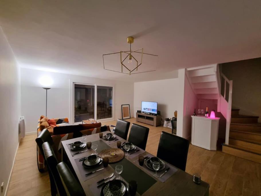 a living room with a table and chairs and a couch at Maison Chaleureuse in Villepinte
