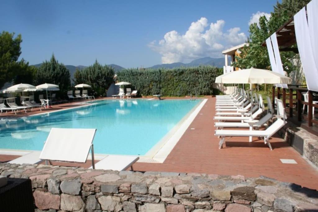 uma piscina com espreguiçadeiras e guarda-sóis em Salerno Mare e Luci Village Palinuro em Palinuro