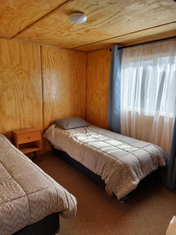 a small bedroom with two beds and a window at OmShanti in Puerto Varas