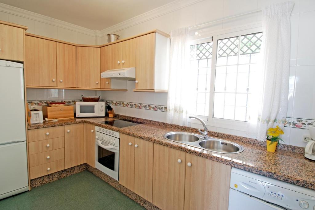 a kitchen with wooden cabinets and a sink and a window at Apartamentos HC Burriana Playa in Nerja