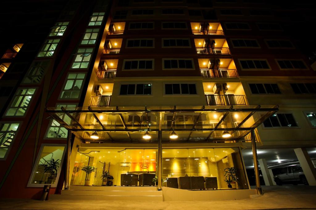 a tall building with a lit up facade at night at Patt Serviced Apartments in Chon Buri