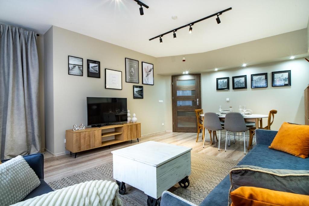 een woonkamer met een bank, een tv en een tafel bij ApartamentySnu, Słoneczny Standard z parkingiem, Centrum in Radom