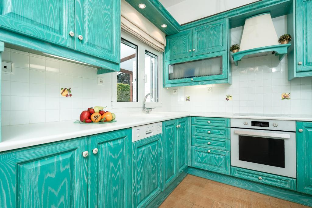 una cocina con armarios azules y un bol de fruta en Coral Cottage House by A&D Properties, en Porto Rafti
