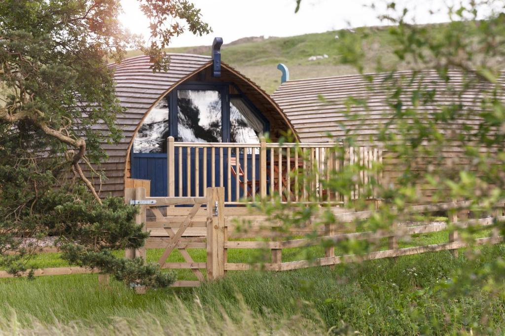 a small cabin with a wooden fence in a field at Finest Retreats - Blackcleugh Glamping in Hexham