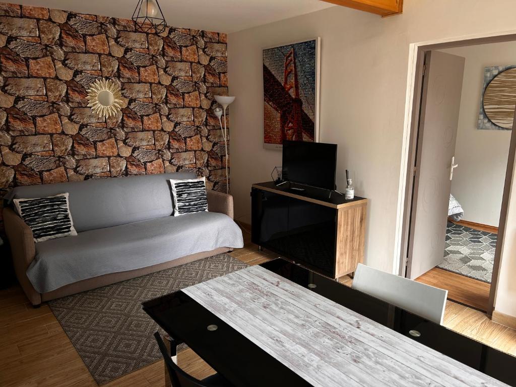 a living room with a couch and a brick wall at Studio indépendant Lisieux in Lisieux