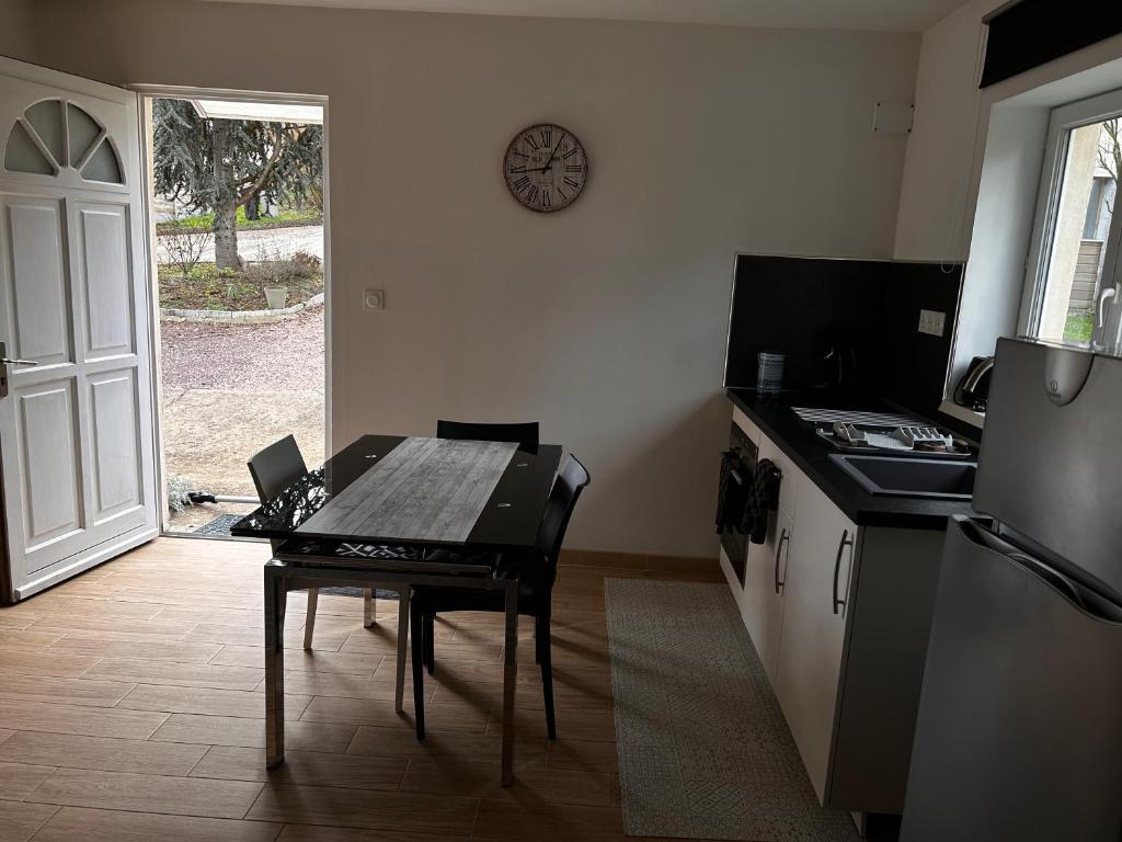 a kitchen with a table and a clock on the wall at Studio indépendant Lisieux in Lisieux