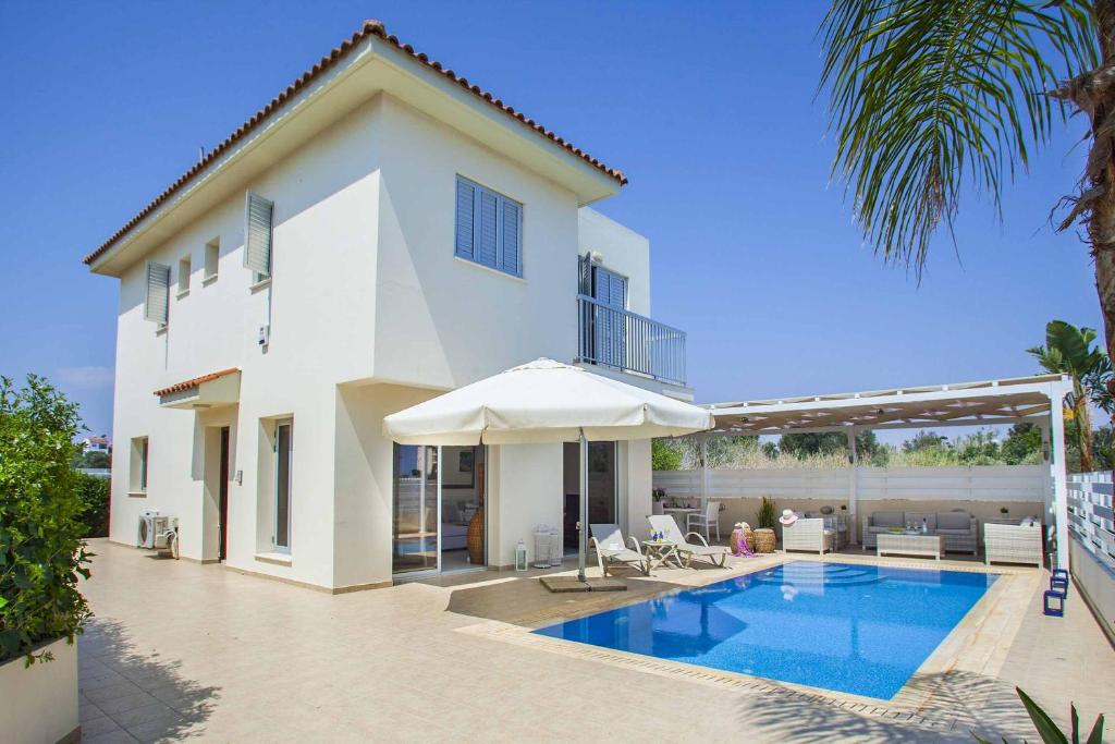 a villa with a swimming pool and a house at Villa Posidonas Three in Protaras