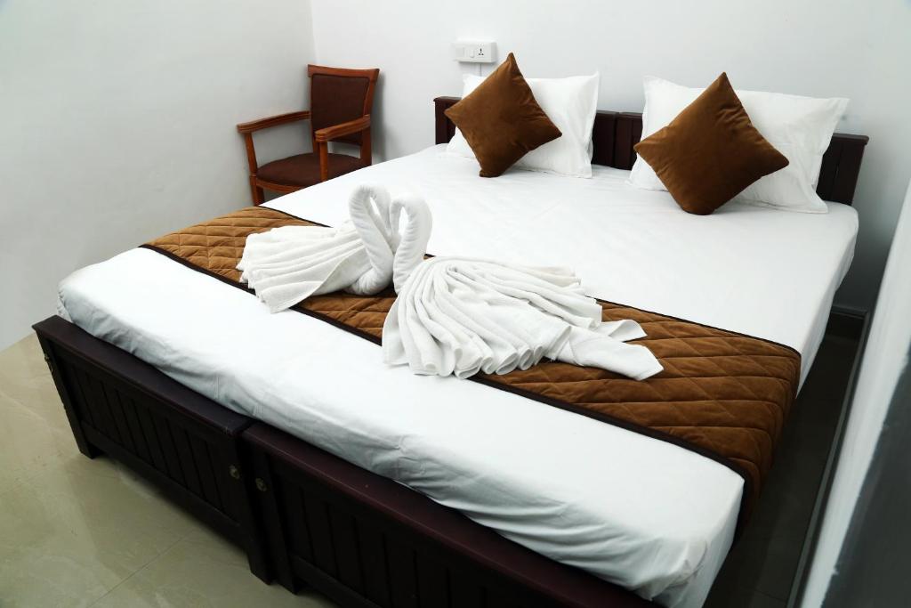 2 Betten in einem Zimmer mit weißer Bettwäsche und Kissen in der Unterkunft AWA Residency in Kochi